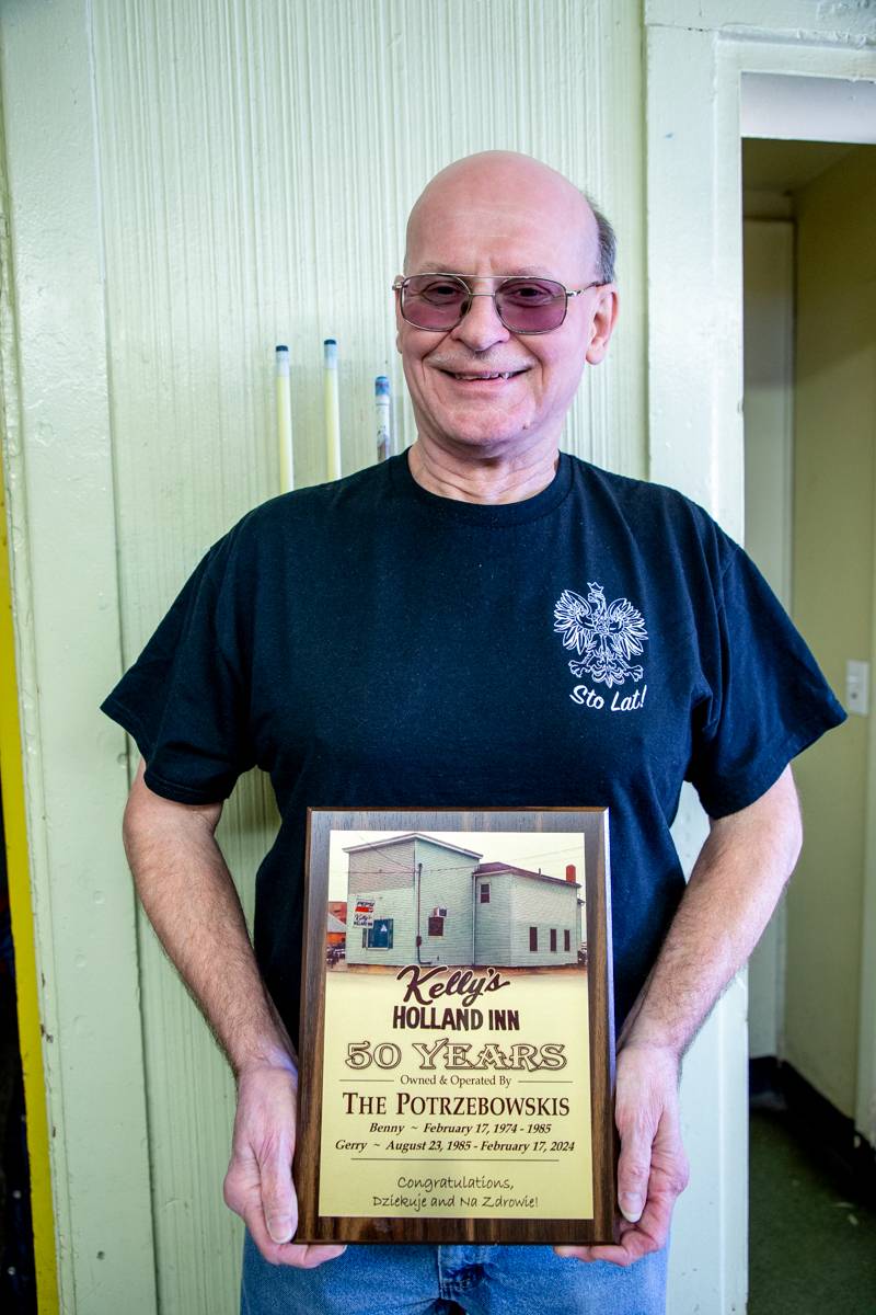 Second generation owner Gerry Potrzebowski in front of his 50th anniversary celebration plaque  Photo by Steve Ognibene
