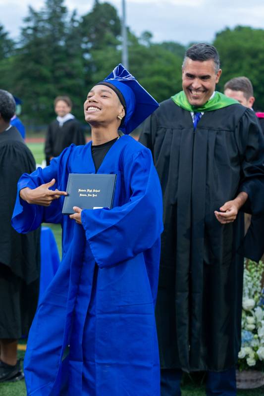 Senior Jevon Griffin looking to the stands at his parents along with Superintendent of Schools Jason Smith smiles after presenting his diploma