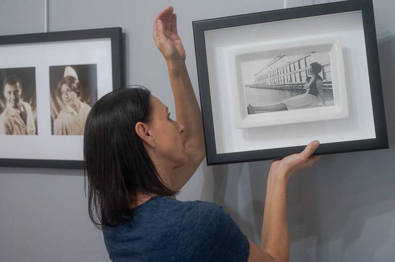 Mary Jo Whitman hangs a photo by Cindy Sherman at GO ART!