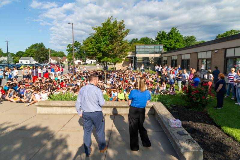 John Kennedy Intermediate principal Paul Kessler and assistant principal Heather McCarthy have morning announcements outside with students for Flag Day.  Photo by Steve Ognibene
