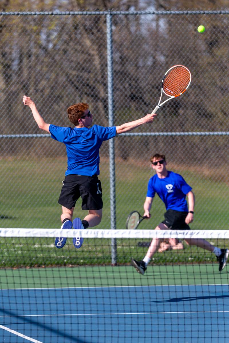 In the air: Aiden Reimer finishes a backhand smash with Will Fulton to win at first doubles.  Photo by Steve Ognibene