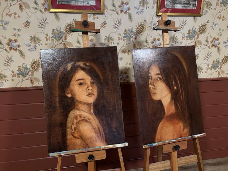 Two easels show paintings of a young girl done by an AP art student.