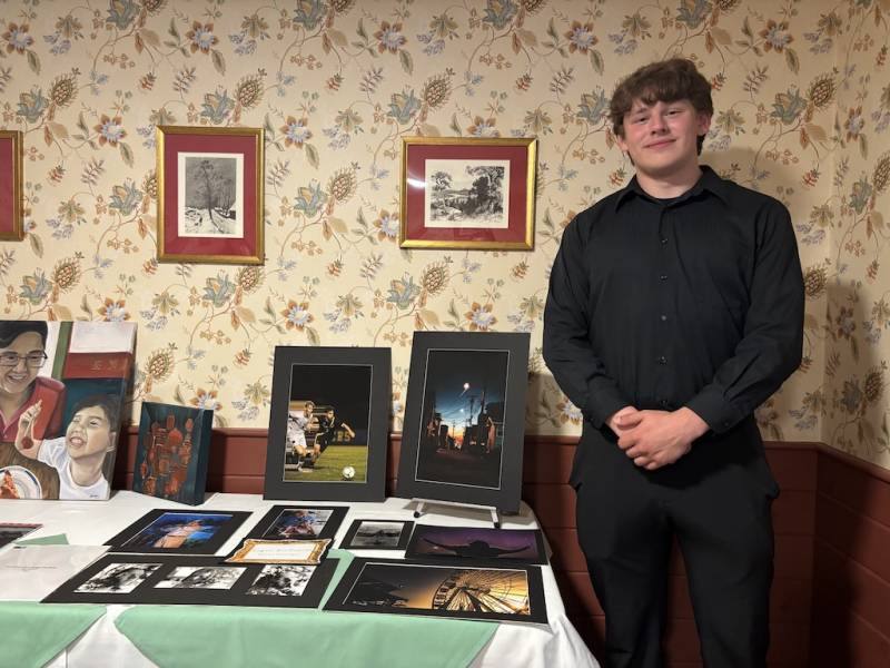Logan DioGuardi stands beside his photographs at the art show.
